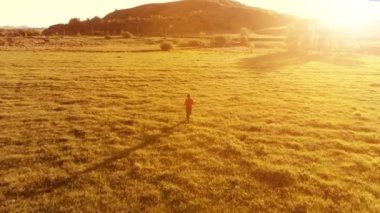 Mükemmel yeşil çayır üzerinde uçan bir sporcu. Dağda gün batımı