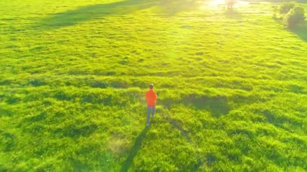 Vuelo sobre el hombre deportivo corriendo en la hierba verde perfecta pradera rural offroad. Puesta de sol en montaña — Vídeos de Stock