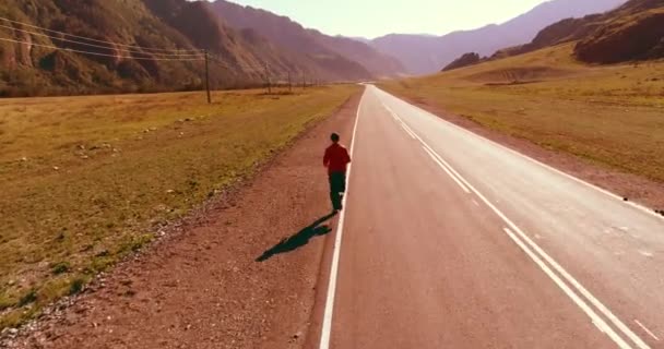 Voo de baixa altitude na frente do homem desportivo na estrada de asfalto perfeito — Vídeo de Stock