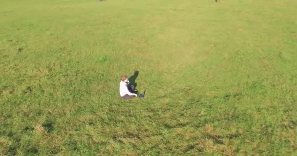 Niedriger Orbitalflug um den Menschen auf grünem Gras mit Notizblock auf gelbem Feld. — Stockvideo