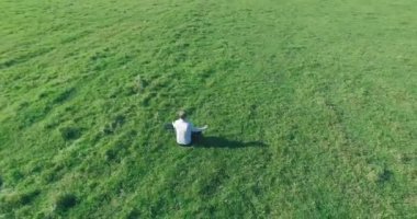 Yeşil çimlerin üzerinde sarı kırsal alanda not defteri olan bir adamın etrafında alçak yörünge uçuşları..