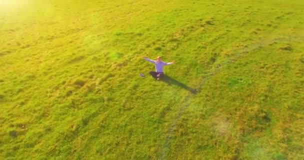 Niedriger Orbitalflug um den Menschen auf grünem Gras mit Notizblock auf gelbem Feld. — Stockvideo