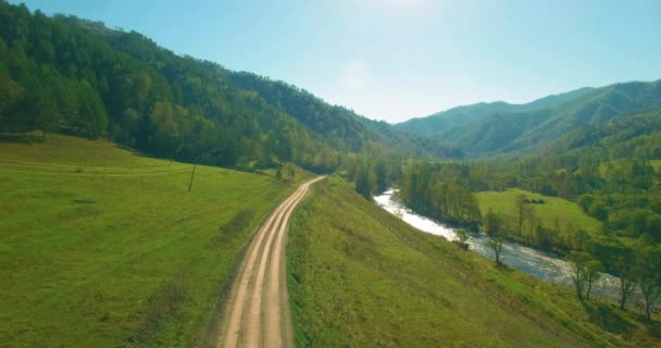 Vol à basse altitude au-dessus d'une rivière de montagne fraîche et rapide avec des rochers au soleil matin d'été. — Video