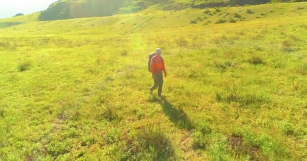 Vol au-dessus du sac à dos randonnée touristique marche à travers le champ de montagne vert. Vallée rurale énorme au jour d'été. — Video