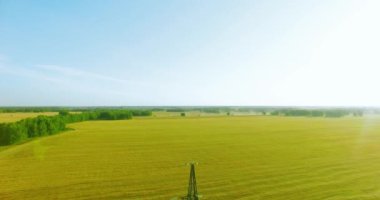 Yüksek voltajlı elektrik kulesi ve yeşil ve sarı alandaki elektrik hatları yakınında dikey hareket.