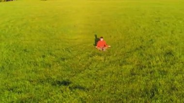 Yeşil çimlerde spor yogacısı üzerinde alçak irtifa radyal uçuş. Dağda gün batımı.