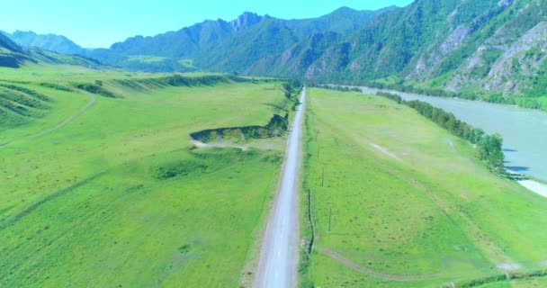 Luchtfoto landelijke bergweg en weide op zonnige zomerochtend. Asfaltweg en rivier. — Stockvideo