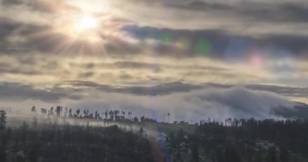 Timelapse di raggi solari serali che emergono attraverso le fredde nuvole nebbiose delle montagne. Tramonto nella nebbia di montagna. — Video Stock