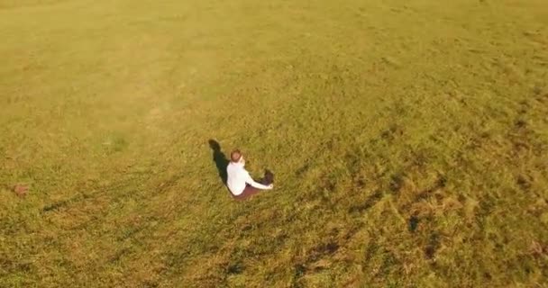 Basso volo orbitale intorno all'uomo su erba verde con blocco note al campo rurale giallo. — Video Stock