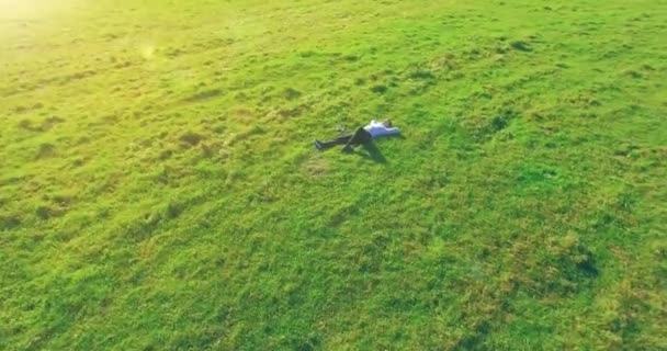 Vôo orbital baixo em torno do homem na grama verde com bloco de caderno no campo rural amarelo. — Vídeo de Stock