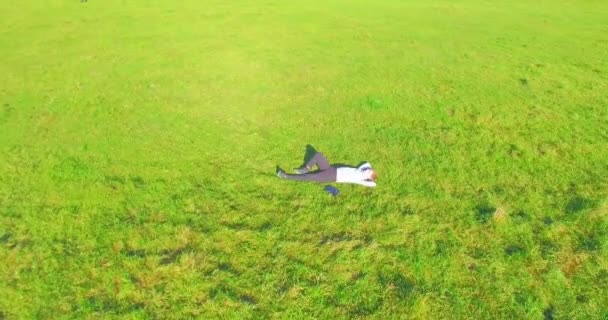 Low orbital flight around man on green grass with notebook pad at yellow rural field. — Stock Video