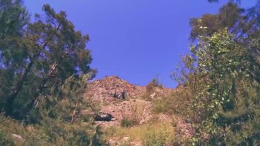 Yazın 4K UHD dağ zaman dilimi. Bulutlar yeşil ağaçları ve güneş ışınlarını hareket ettirir.