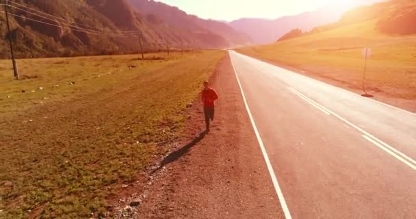 Vuelo de baja altitud frente al deportista en el camino perfecto de asfalto — Vídeo de stock