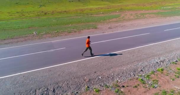 Voo de baixa altitude na frente do homem desportivo na estrada de asfalto perfeito — Vídeo de Stock