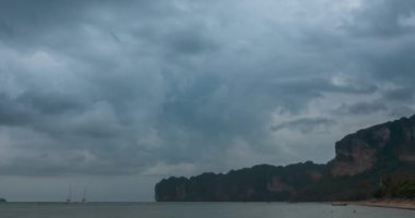 Kumsalda ve teknelerle deniz manzarasında yağmur bulutları hızlanıyor. Okyanusta tropik fırtına.