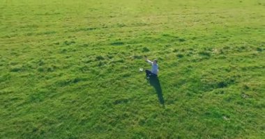 Yeşil çimlerin üzerinde sarı kırsal alanda not defteri olan bir adamın etrafında alçak yörünge uçuşları..