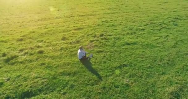 Lage baanvlucht rond mens op groen gras met notitieblok op geel landelijk veld. — Stockvideo