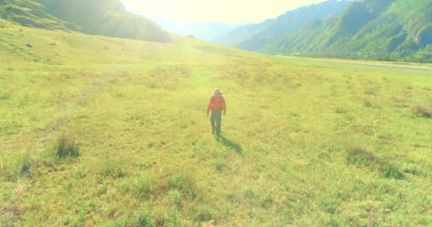 Flug über den Rucksack Wandertourist zu Fuß über grüne Bergwiese. Riesiges ländliches Tal an Sommertagen. — Stockvideo