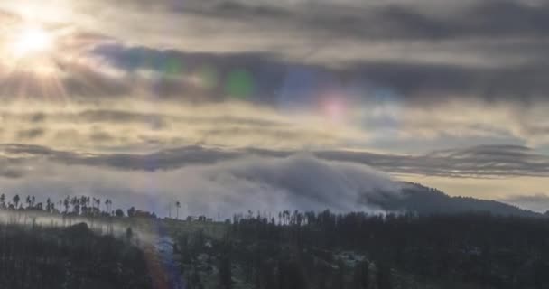 Timelapse de raios de sol à noite emergindo através das nuvens nebulosas frias nas montanhas. Pôr do sol no nevoeiro da montanha. — Vídeo de Stock