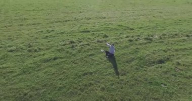 Yeşil çimlerin üzerinde sarı kırsal alanda not defteri olan bir adamın etrafında alçak yörünge uçuşları..