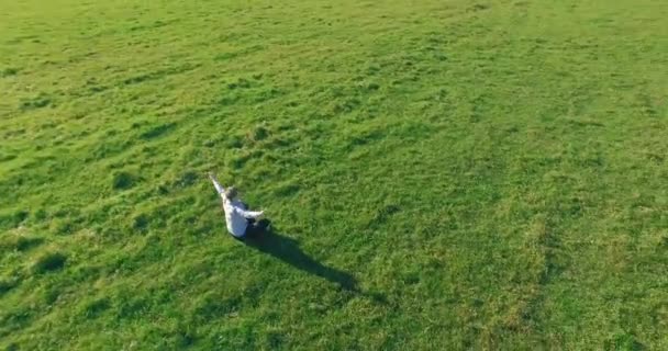 Basso volo orbitale intorno all'uomo su erba verde con blocco note al campo rurale giallo. — Video Stock