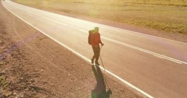 Asfalt yolda yürüyen otostopçu turist üzerinden uçuş. Yaz günü büyük bir kırsal vadi. Sırt çantalı gezgin..