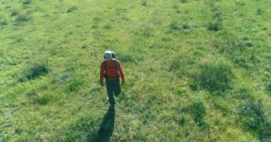 Sırt çantasıyla gezen turist yeşil dağ tarlasında yürüyor. Yaz günü büyük kırsal vadi.