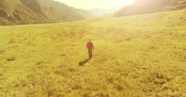 Voo sobre mochila caminhadas turista caminhando através de campo de montanha verde. Vale rural enorme no dia de verão. — Vídeo de Stock