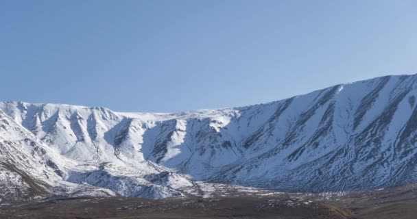 Timelapse de movimiento del sol en el cielo cristalino sobre la cima de la montaña de nieve. Hierba amarilla en el prado de otoño. Naturaleza salvaje sin fin. — Vídeo de stock