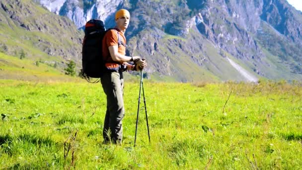 Pěší turistika muž na zelené horské louky s batohem. Letní sportovní a rekreační koncepce. — Stock video