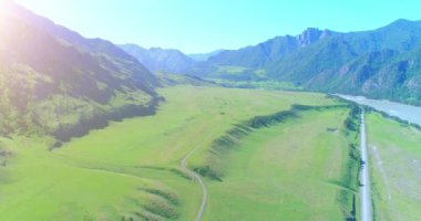 Güneşli yaz sabahında havadan kırsal dağ yolu ve çayır. Asfalt karayolu ve nehir.