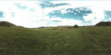 360 VR 'lık güzel bir dağ çayırı zaman dilimi. Yaz ya da sonbahar zamanında. Bulutlar, yeşil çimenler ve güneş ışınları.