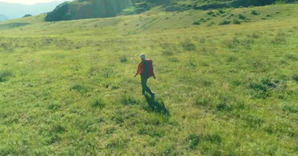 Vol au-dessus du sac à dos randonnée touristique marche à travers le champ de montagne vert. Vallée rurale énorme au jour d'été. — Video