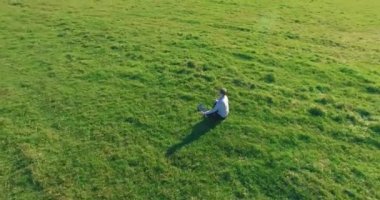Yeşil çimlerin üzerinde sarı kırsal alanda not defteri olan bir adamın etrafında alçak yörünge uçuşları..