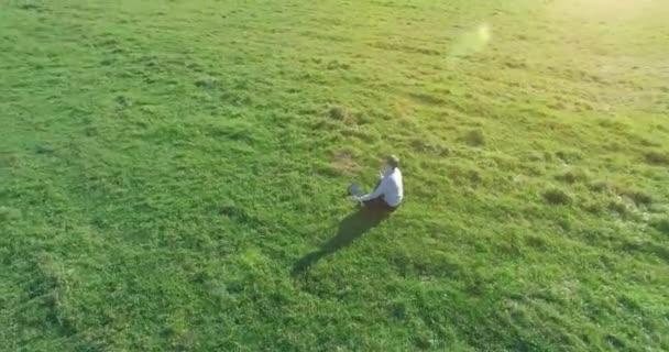 Lage baanvlucht rond mens op groen gras met notitieblok op geel landelijk veld. — Stockvideo