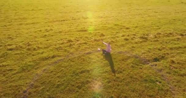 Lage baanvlucht rond mens op groen gras met notitieblok op geel landelijk veld. — Stockvideo