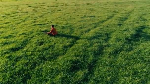 Низькогірний радіальний політ над спортивною людиною йоги на ідеальній зеленій траві. Захід сонця в горах . — стокове відео