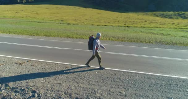 Flyg över liftare turist promenader på asfalterad väg. Enorm lantlig dal på sommardagen. Ryggsäck vandring kille. — Stockvideo