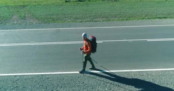 Vlucht over lifter toerist wandelen op asfalt weg. Enorme landelijke vallei op zomerdag. Rugzakwandelaar. — Stockvideo