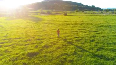 Mükemmel yeşil çayır üzerinde uçan bir sporcu. Dağda gün batımı