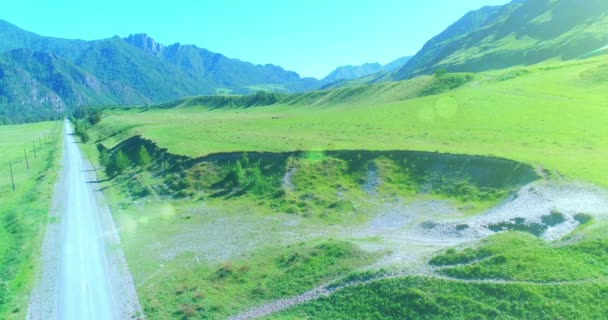 Luchtfoto landelijke bergweg en weide op zonnige zomerochtend. Asfaltweg en rivier. — Stockvideo