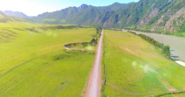 Güneşli yaz sabahında havadan kırsal dağ yolu ve çayır. Asfalt karayolu ve nehir.