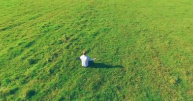 Yeşil çimlerin üzerinde sarı kırsal alanda not defteri olan bir adamın etrafında alçak yörünge uçuşları..