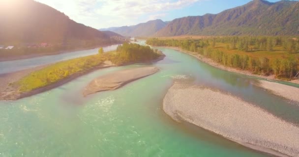 Vol à basse altitude au-dessus d'une rivière de montagne fraîche et rapide avec des rochers au soleil matin d'été. — Video