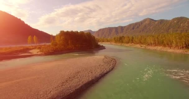 4k UHD航空ビュー。晴れた夏の朝に新鮮な冷たい山の川の上に低飛行。地平線の緑の木と太陽の光 — ストック動画