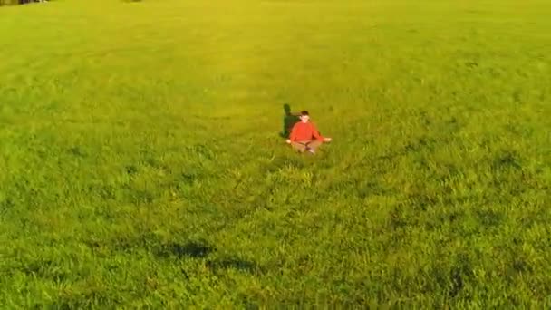 Lage hoogte radiale vlucht over sport yoga man op perfect groen gras. Zonsondergang in de bergen. — Stockvideo