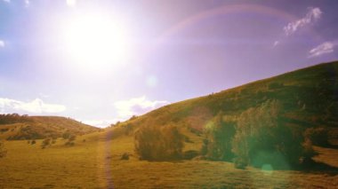 Yazın 4K UHD dağ çayırı zaman dilimi. Bulutlar, ağaçlar, yeşil çimenler ve güneş ışınları hareketi.