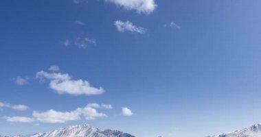 Güneş 'in kristal berrak gökyüzünde, kar dağının tepesindeki bulutlarla hareket zamanı. Sonbahar yüksek rakımlı çayırlarda sarı çimenler. Vahşi sonsuz doğa..
