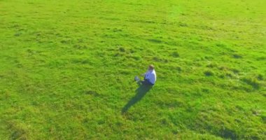 Yeşil çimlerin üzerinde sarı kırsal alanda not defteri olan bir adamın etrafında alçak yörünge uçuşları..