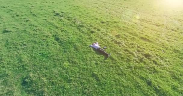 Lage baanvlucht rond mens op groen gras met notitieblok op geel landelijk veld. — Stockvideo